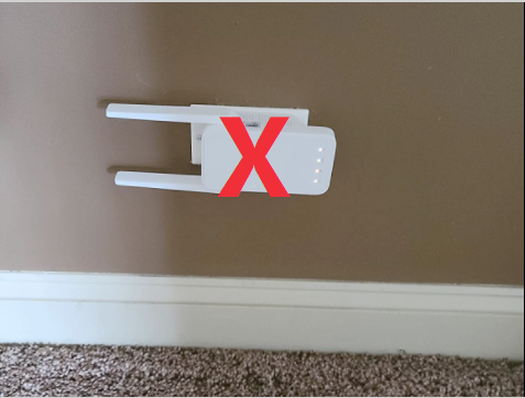 Photo showing an error case of the extender plugged directly into a close-to-ground wall outlet, with its external antennas parallel to the floor.