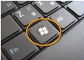 Close-up of a laptop keyboard with the Windows key highlighted in an orange circle.