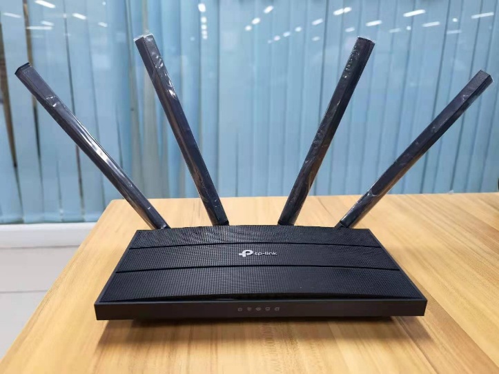 TP-Link router with four antennas spread outward at an Angle of 30°, placed on a wooden table.