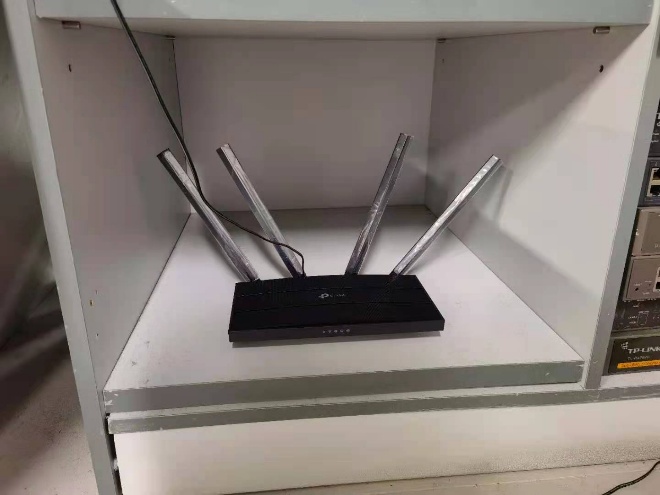 TP-Link router placed inside an enclosed cabinet shelf, restricting signal coverage.