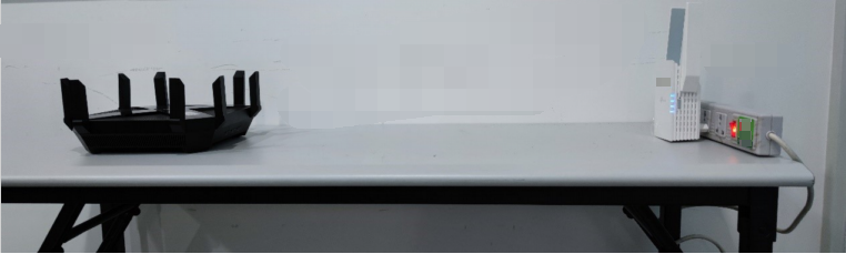 Photo showing extender and router on a desk at the same height, with extender facing the router.